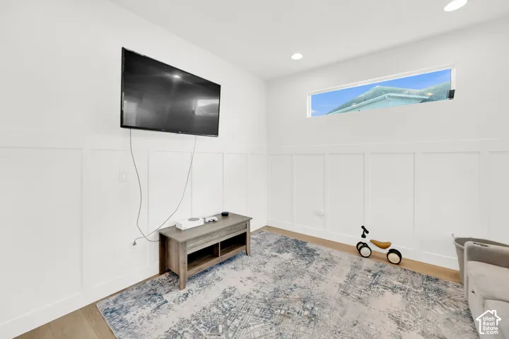 Living room with a decorative wall, a wainscoted wall, wood finished floors, and recessed lighting
