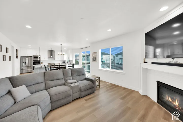 Living area with light wood-style flooring, a tiled fireplace, and a chandelier