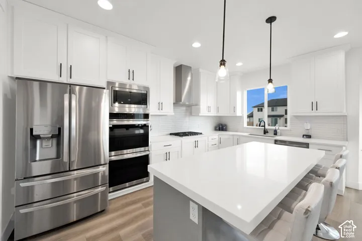 Kitchen featuring stainless steel appliances, light wood-type flooring, a kitchen island, and white cabinets