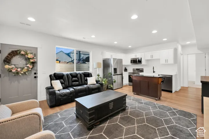 Living area with light wood-type flooring and recessed lighting