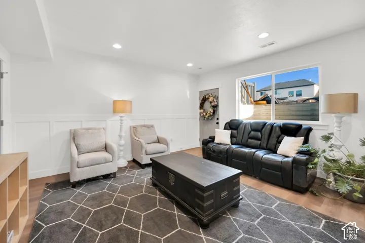 Living area featuring dark wood-style floors, a wainscoted wall, a decorative wall, and recessed lighting