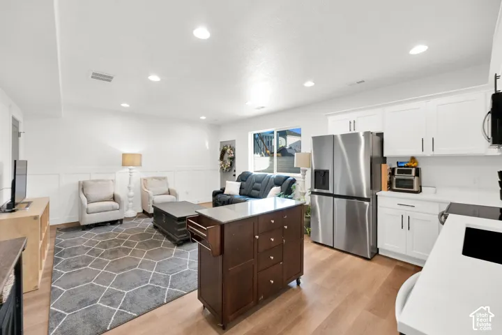 Kitchen with open floor plan, stainless steel appliances, wainscoting, light wood-style flooring, and recessed lighting