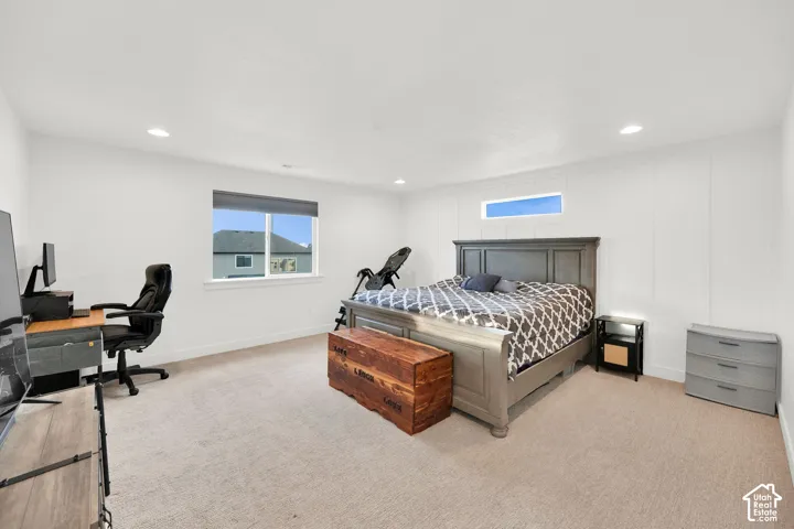 Bedroom with a desk, light colored carpet, and recessed lighting