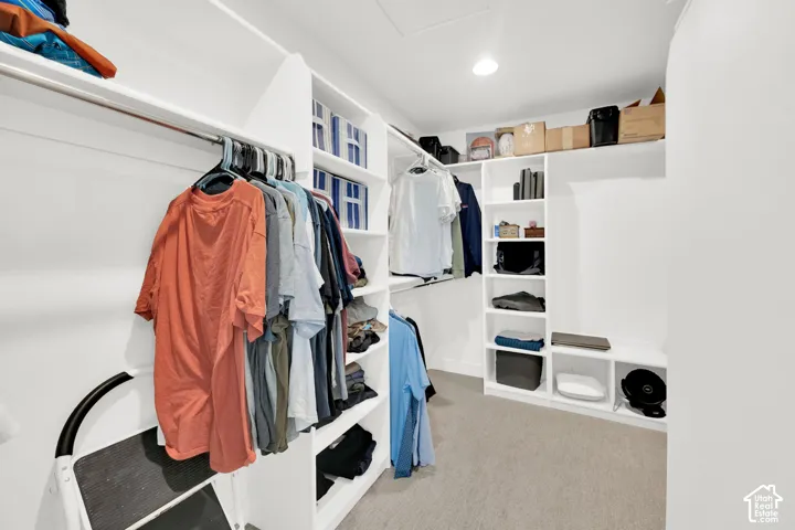 Walk in closet with light colored carpet and attic access