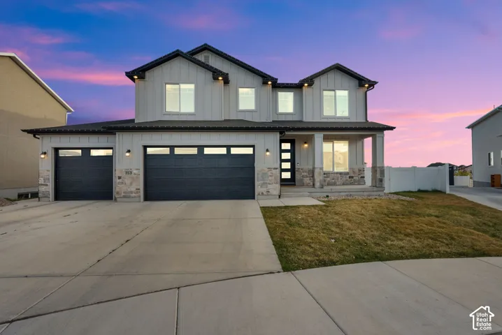 Modern inspired farmhouse featuring board and batten siding, a porch, concrete driveway, and stone siding