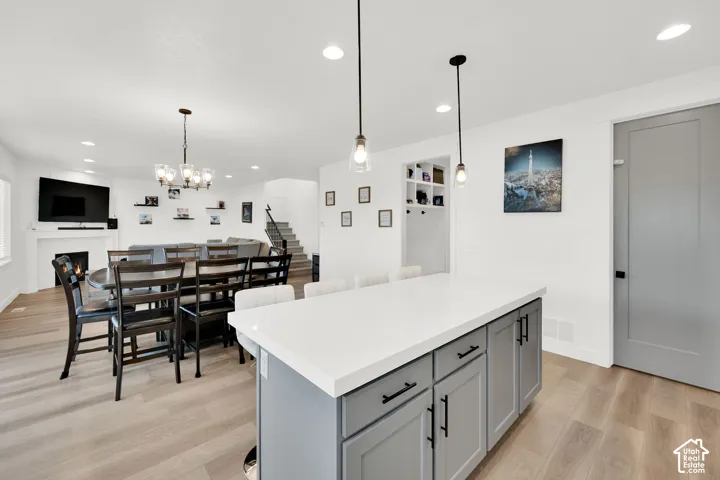 Kitchen with a kitchen island, light wood finished floors, a kitchen bar, open floor plan, and gray cabinetry