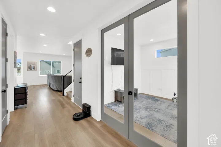 Corridor with light wood finished floors, recessed lighting, and french doors