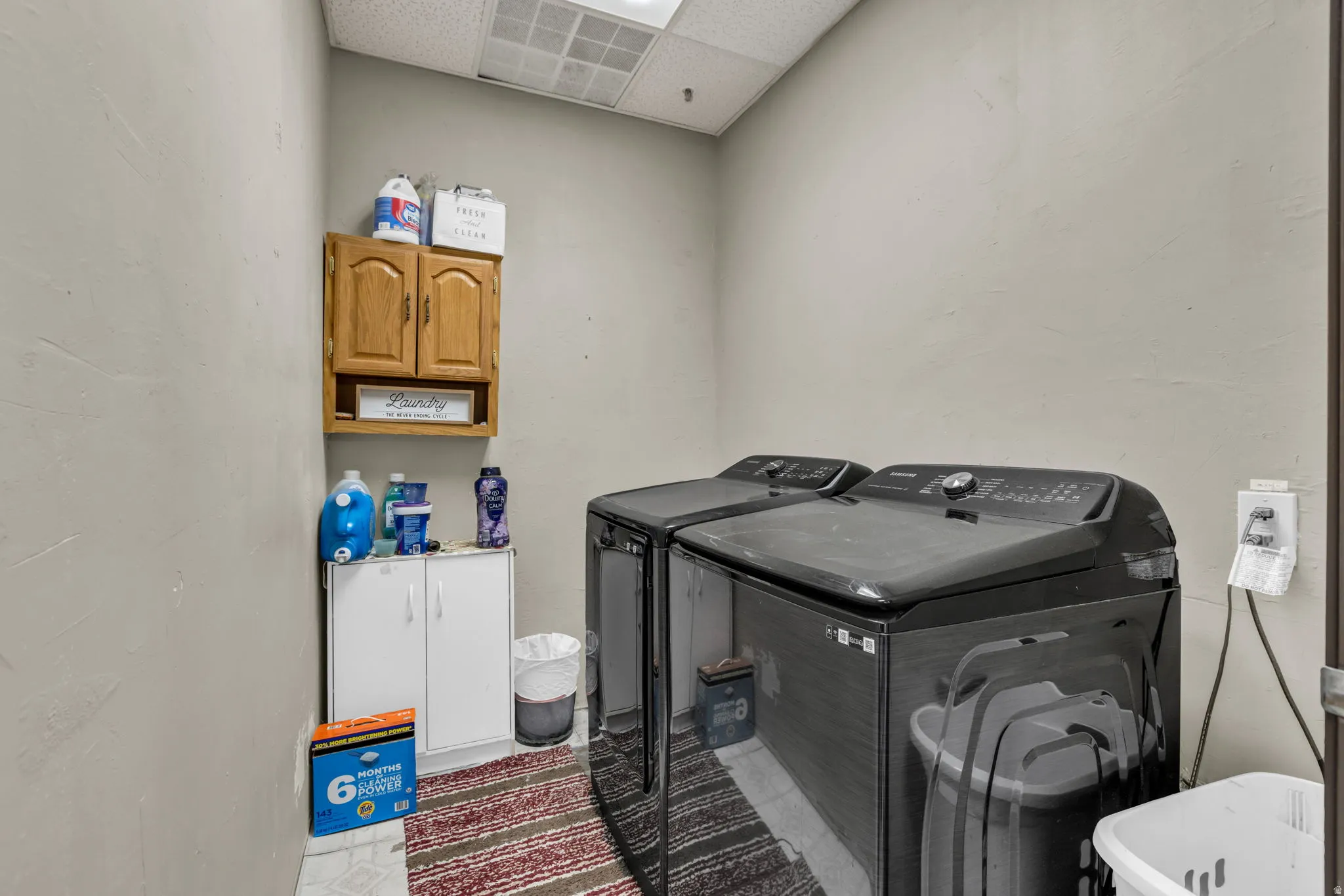 Laundry area with a drop ceiling, independent washer and dryer, and cabinet space