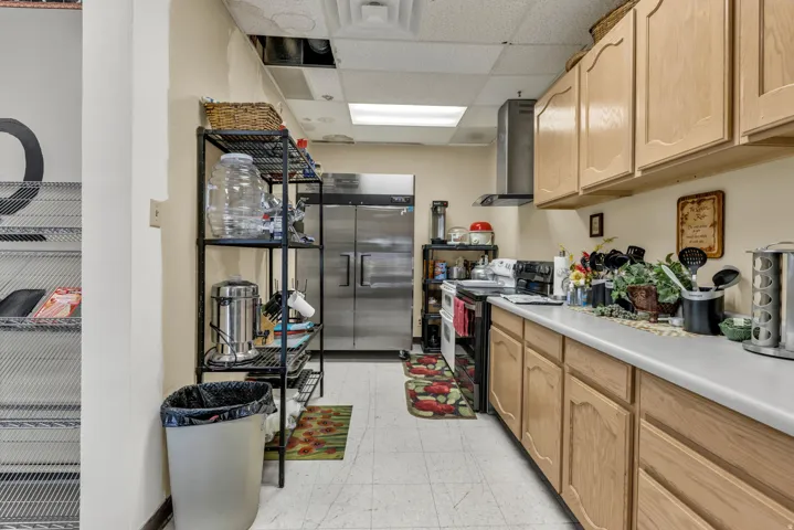 Kitchen with a drop ceiling, light countertops, high end refrigerator, electric range, and light wood finish cabinets
