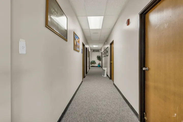 Corridor with a drop ceiling and light carpet