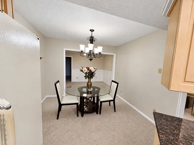 Recessed entrance featuring a chandelier, light carpeting, and crown molding