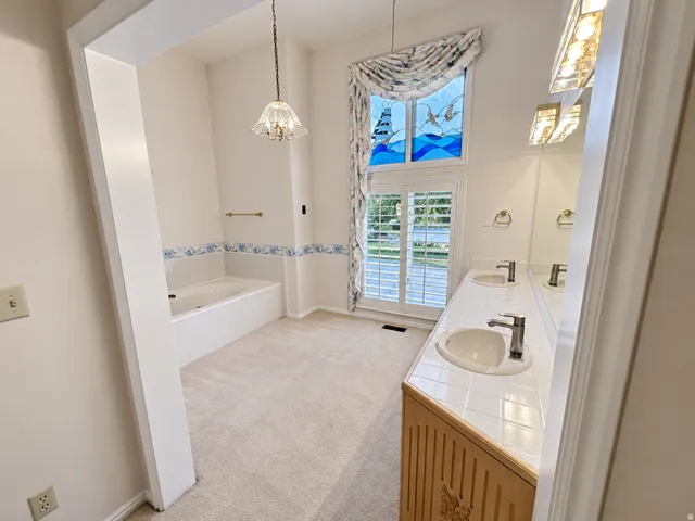 Double vanity with tile countertop, integrated sinks, and contemporary fixtures