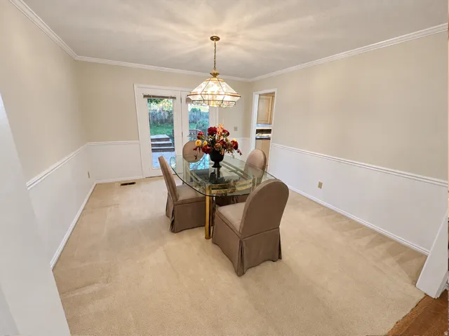 Recessed ceiling with central chandelier, crown molding, chair rail molding, and glass panel French doors