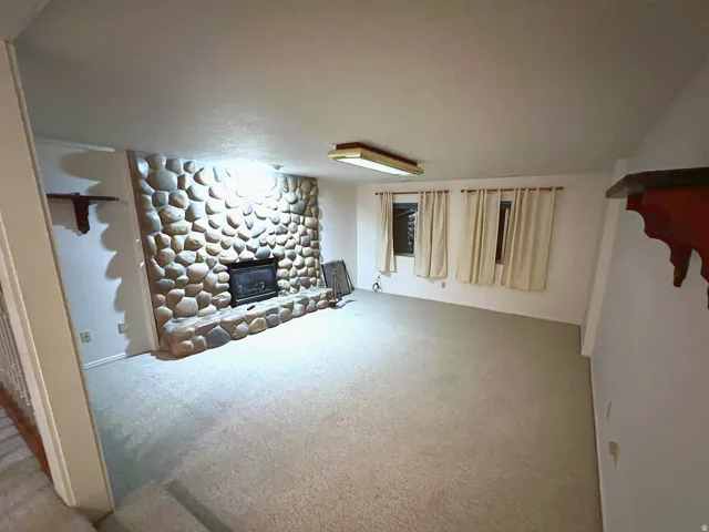 Stone surround fireplace with hearth, wall-to-wall carpeting, and multiple windows
