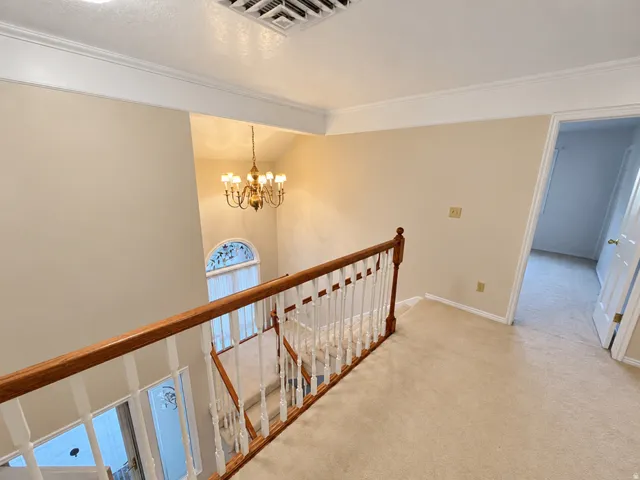 Overlooking staircase with wood railing, carpeted flooring, and decorative lighting fixture