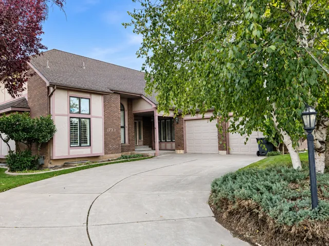 Brick and stucco exterior with multiple windows, an attached two-car garage, and a concrete driveway