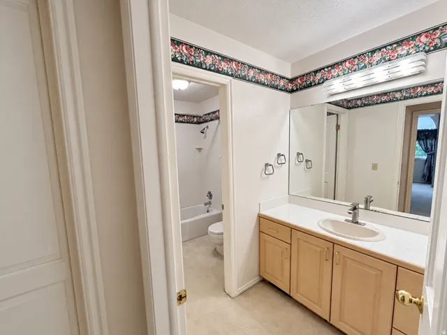 Vanity with a built-in sink, solid surface countertop, wood-finish cabinetry, and an integrated mirror