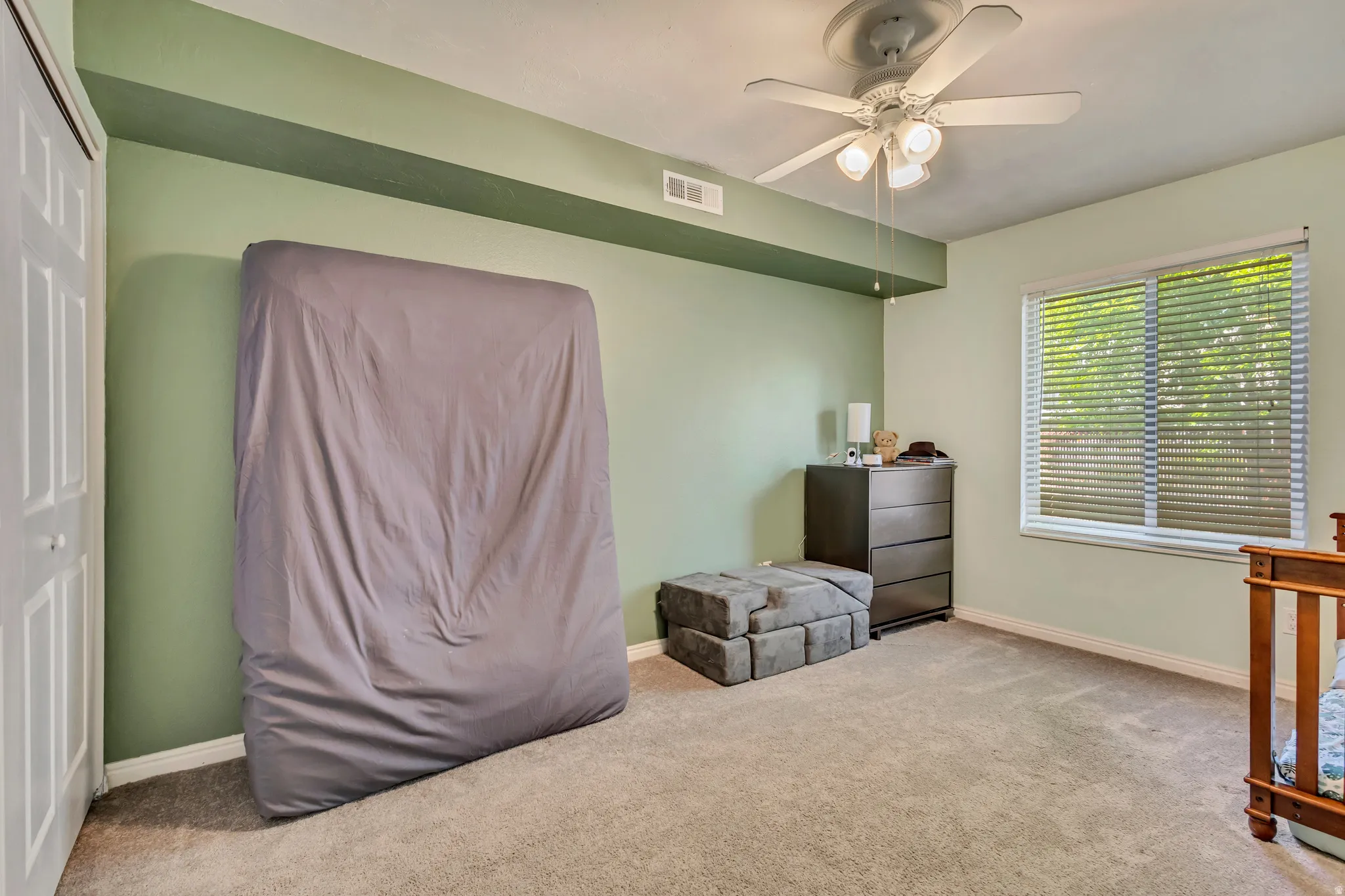 Bedroom with light colored carpet and a ceiling fan