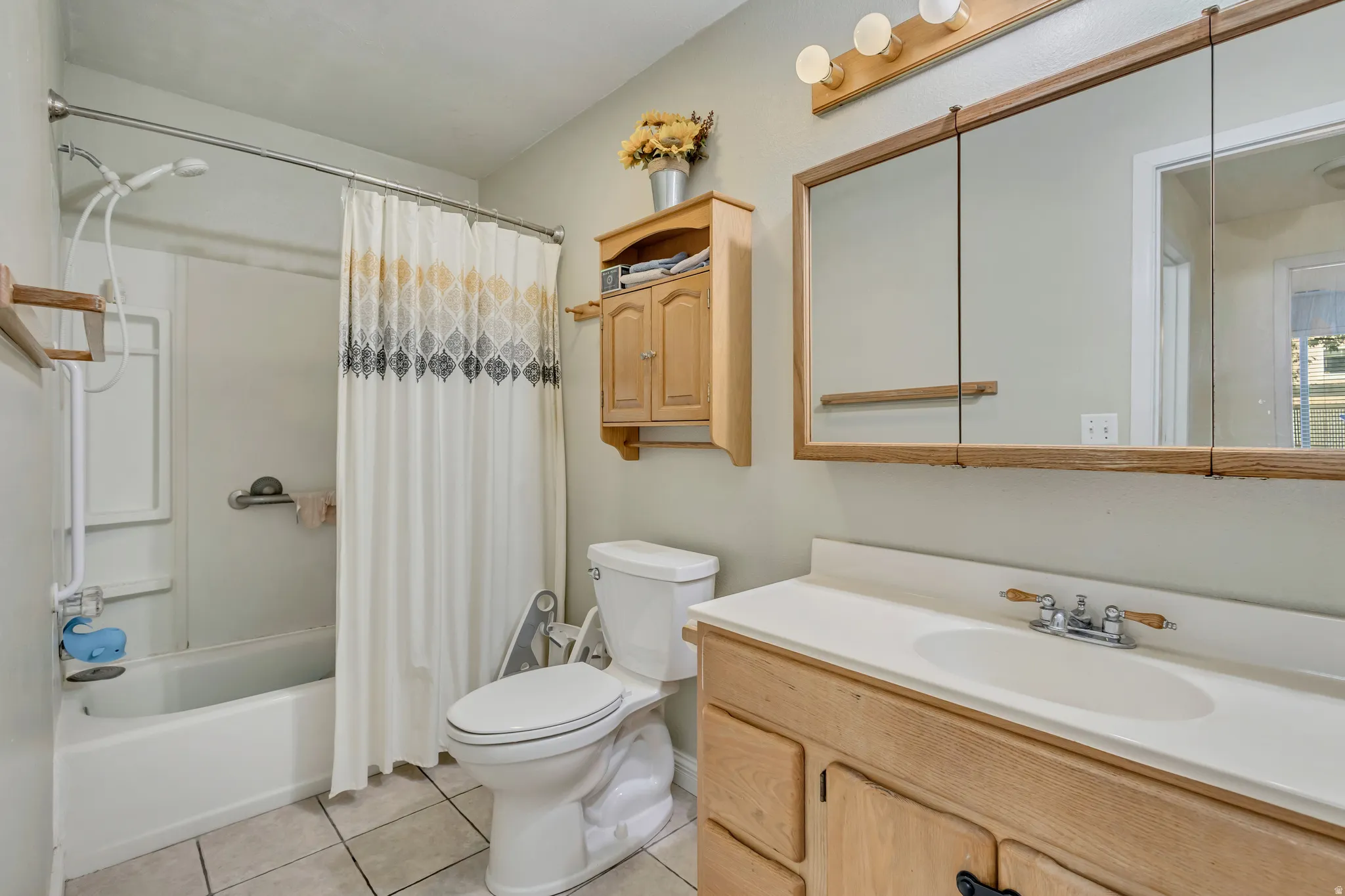 Bathroom featuring vanity, shower / bath combo, and light tile patterned floors