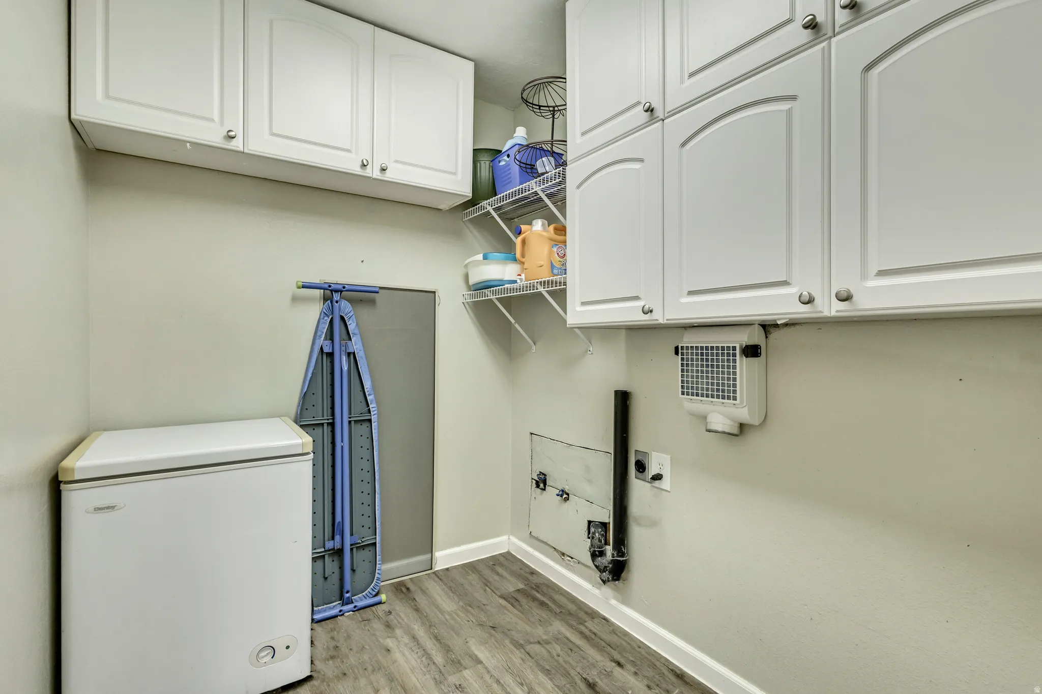 Laundry area featuring cabinet space, light wood-type flooring, washer hookup, and electric dryer hookup