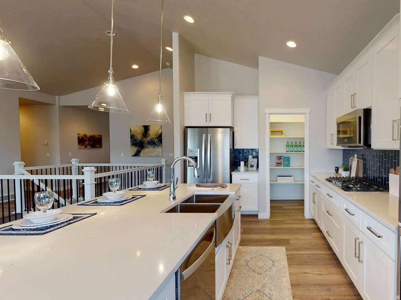 Kitchen featuring decorative backsplash, light wood finished floors, white cabinets, vaulted ceiling, and stainless steel appliances