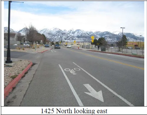 View of asphalt road featuring curbs, a mountain view, and sidewalks