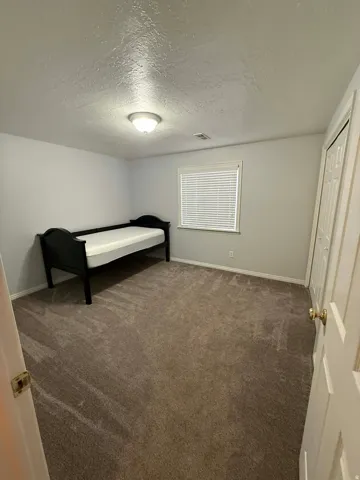 Bedroom featuring a textured ceiling and dark carpet