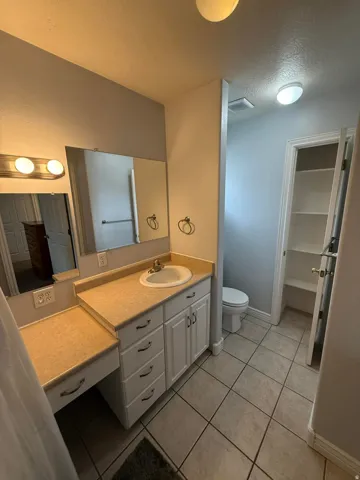 Bathroom with a textured ceiling, vanity, light tile patterned flooring, and a closet
