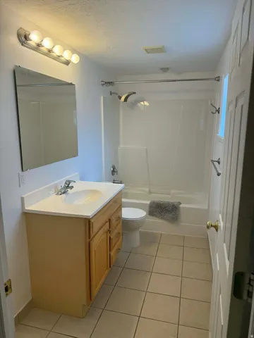 Full bathroom featuring vanity, light tile patterned floors, bathing tub / shower combination, and a textured ceiling