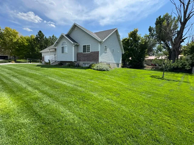 View of property exterior with a lawn, an attached garage, and view of wooded area