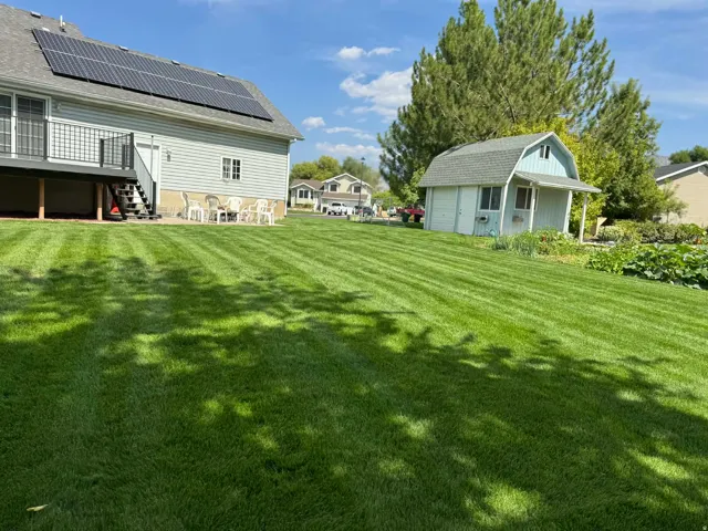 View of green lawn with an outbuilding, a detached garage, a deck, and a patio area
