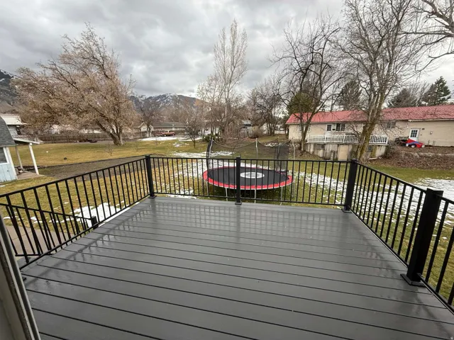 Wooden deck with a trampoline, a mountain view, a lawn, and a residential view