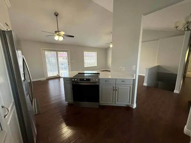 Kitchen with vaulted ceiling, stainless steel appliances, dark wood-style flooring, a peninsula, and white cabinetry