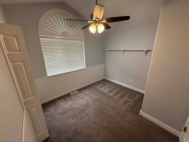 Unfurnished room with dark carpet and a ceiling fan