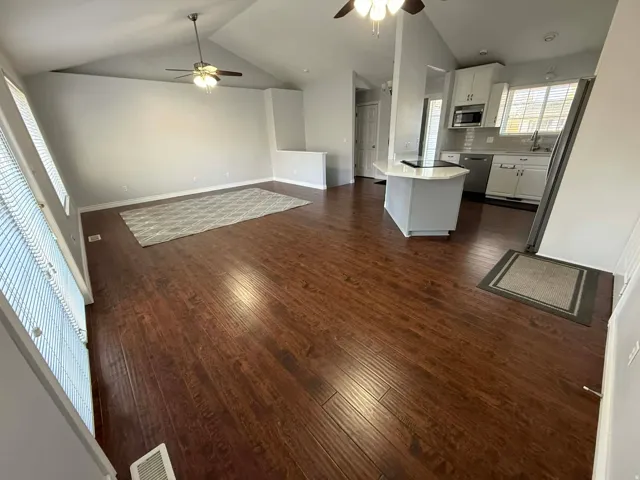 Unfurnished living room with ceiling fan and dark wood-style flooring