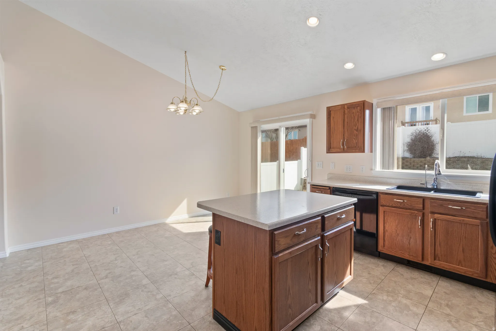 Kitchen featuring lofted ceiling, plenty of natural light, a center island, black dishwasher, and light countertops