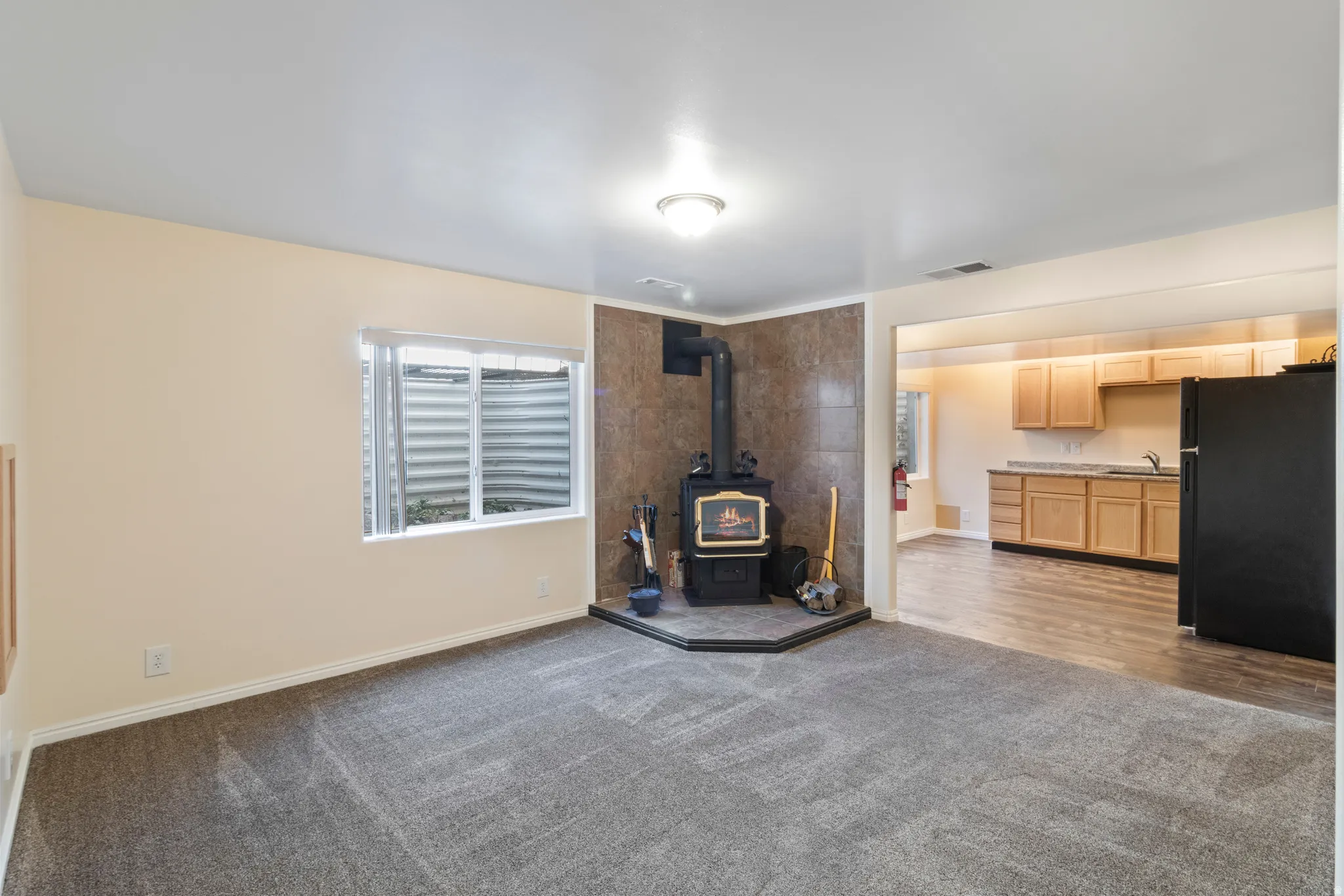 Unfurnished living room with dark carpet and a wood stove