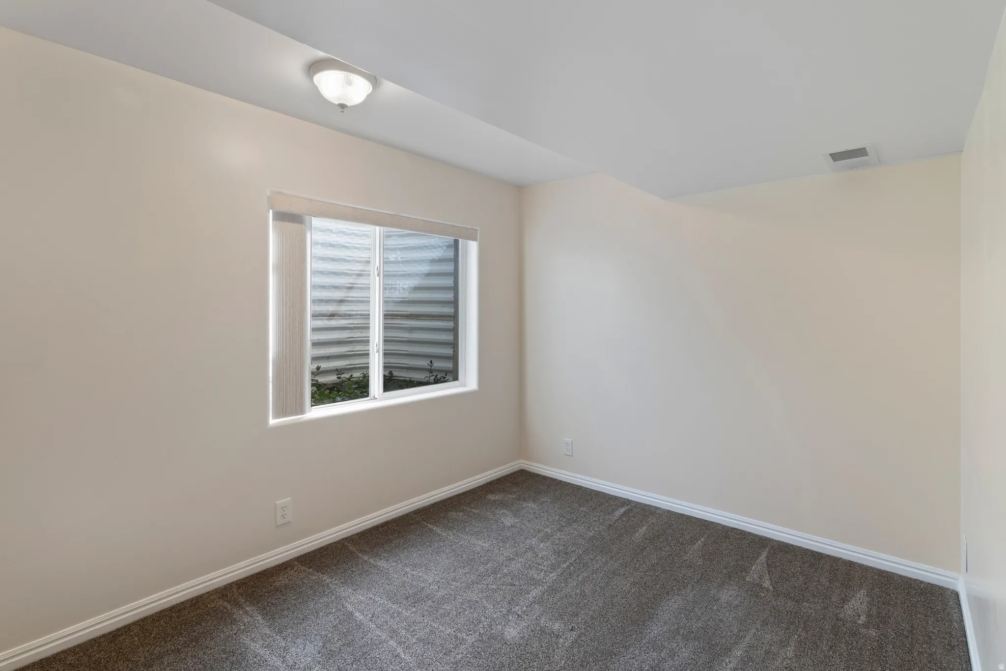 Spare room with dark carpet and baseboards