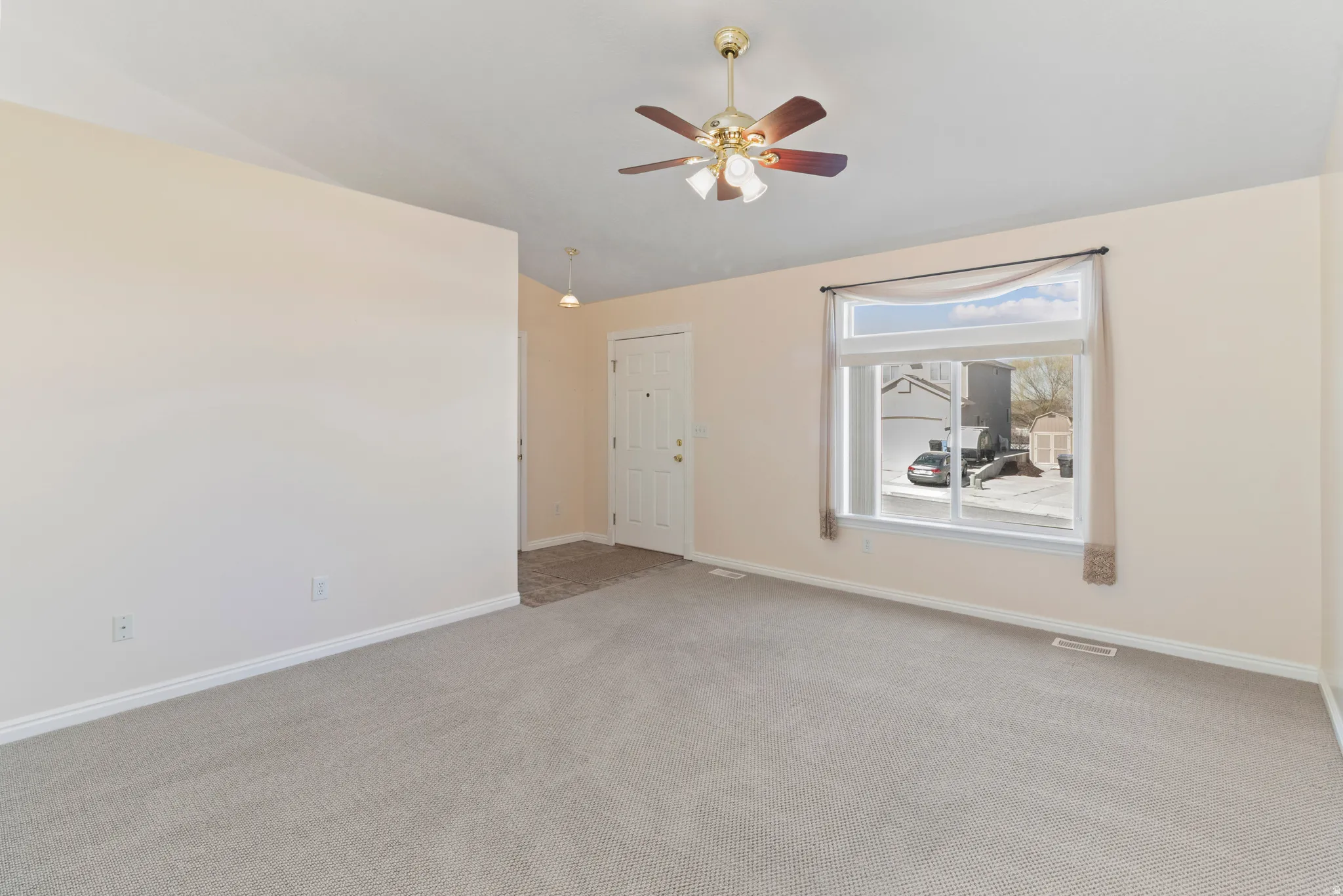 Spare room with light colored carpet, a ceiling fan, and vaulted ceiling