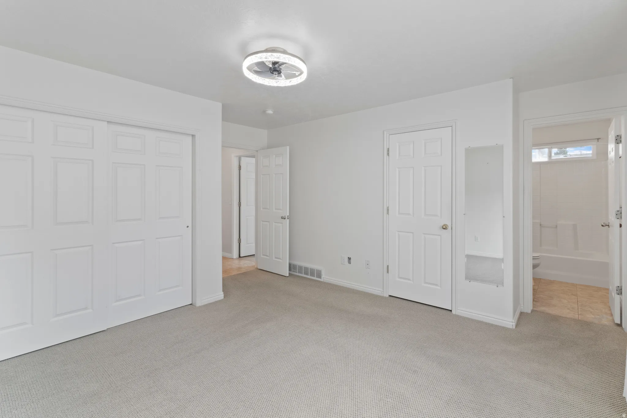 Unfurnished bedroom with light carpet, ensuite bathroom, and a closet