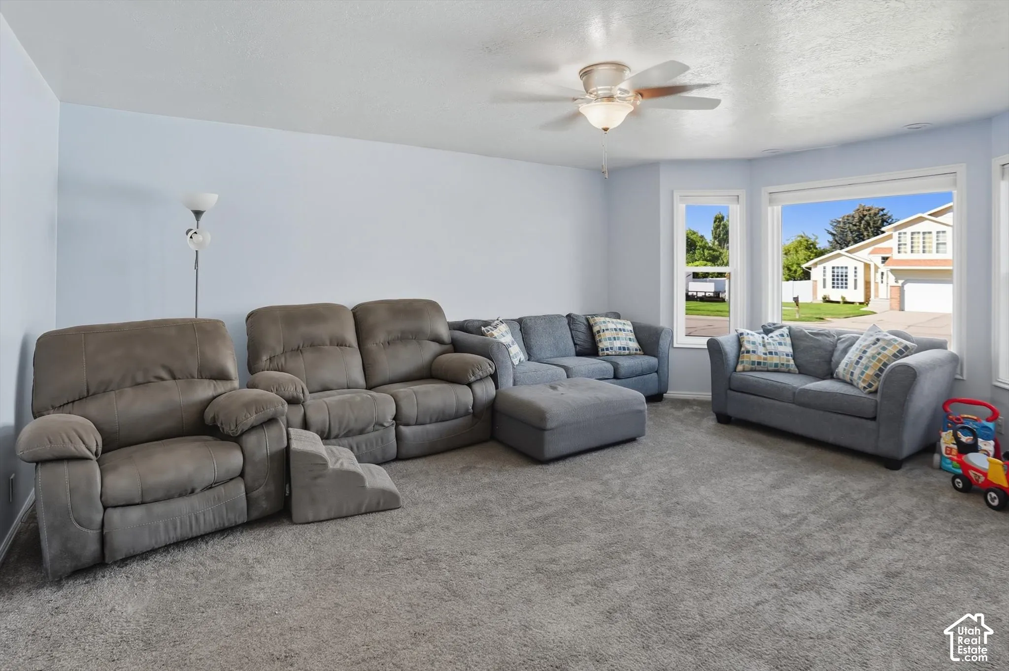 Carpeted living room featuring a ceiling fan and a textured ceiling