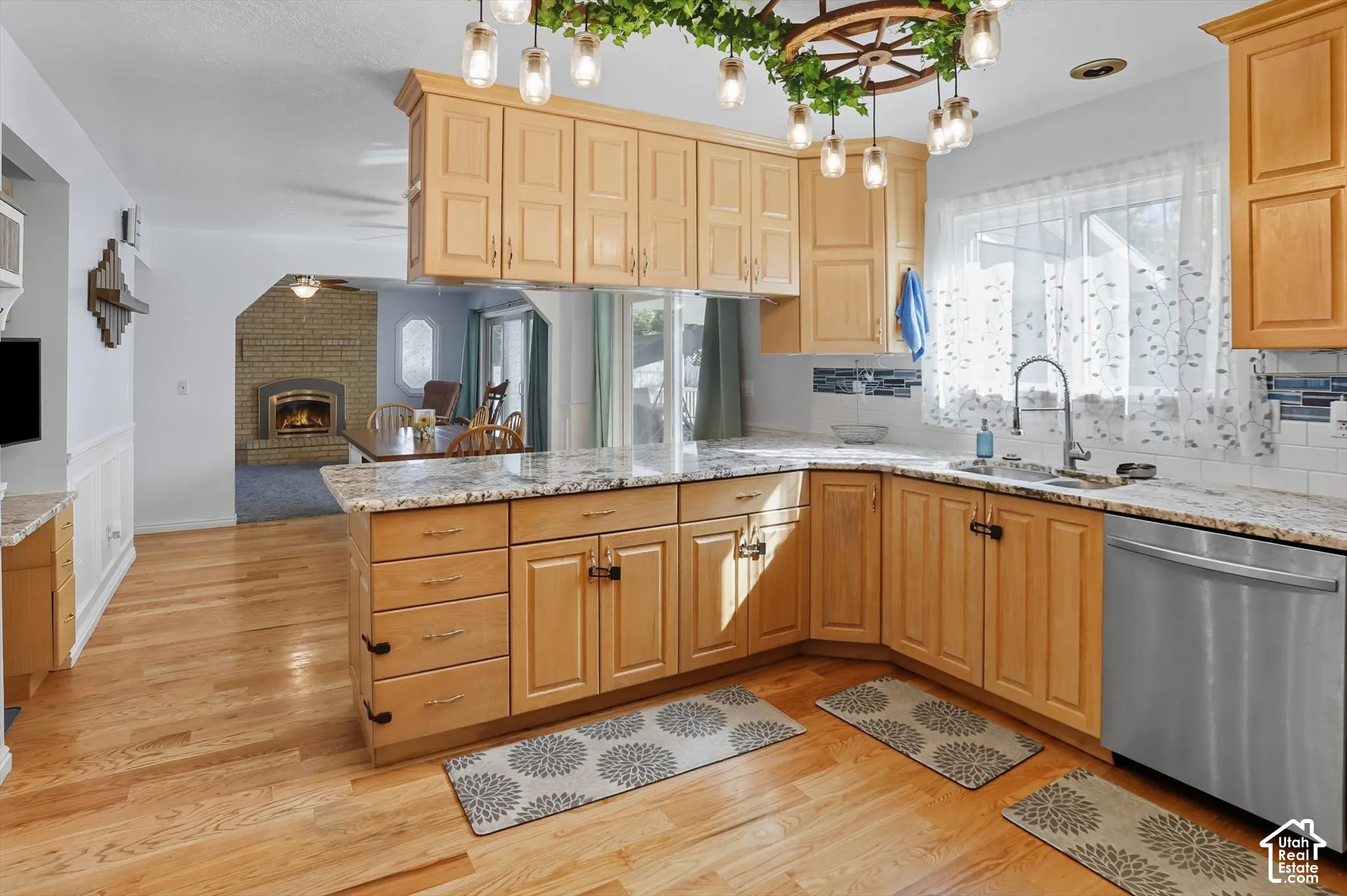 Kitchen with a peninsula, dishwasher, light stone counters, and open floor plan