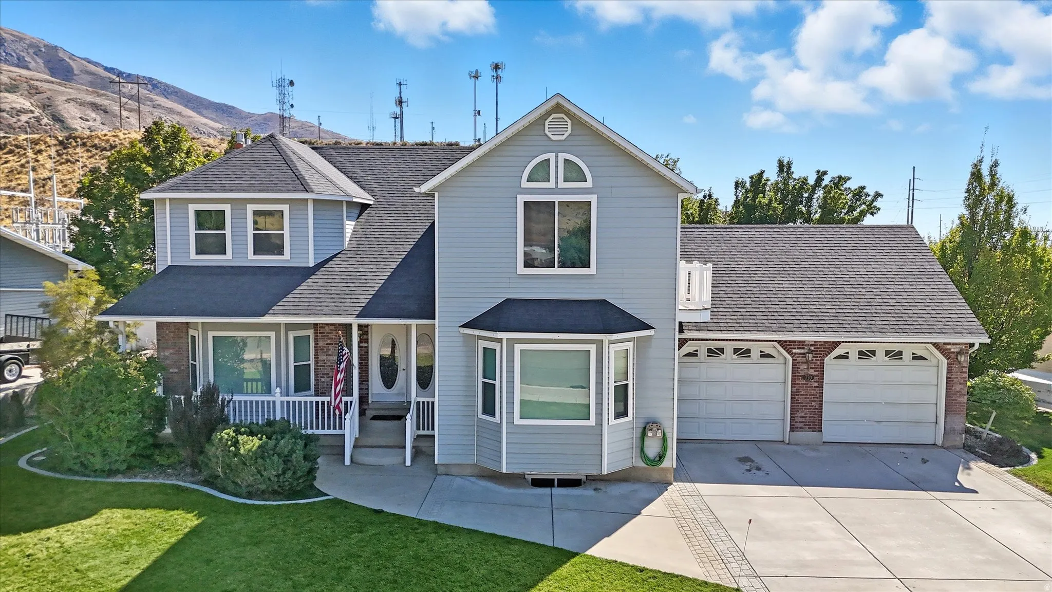 Traditional-style home with brick siding, covered porch, driveway, an attached garage, and roof with shingles