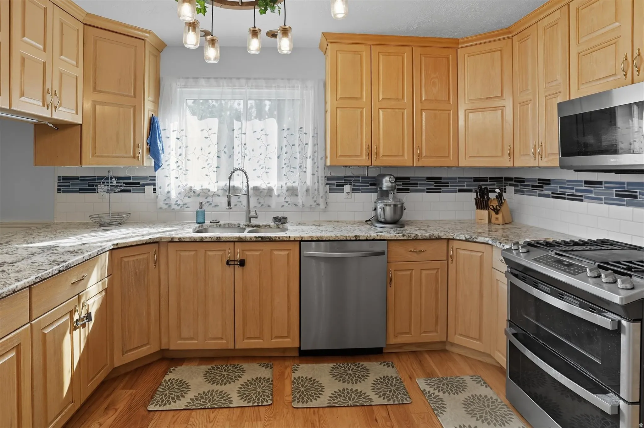 Kitchen with stainless steel appliances, light stone counters, and tasteful backsplash