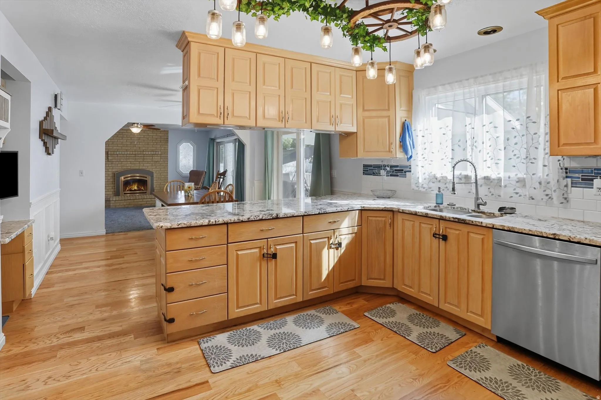 Kitchen with a peninsula, dishwasher, light stone counters, and open floor plan