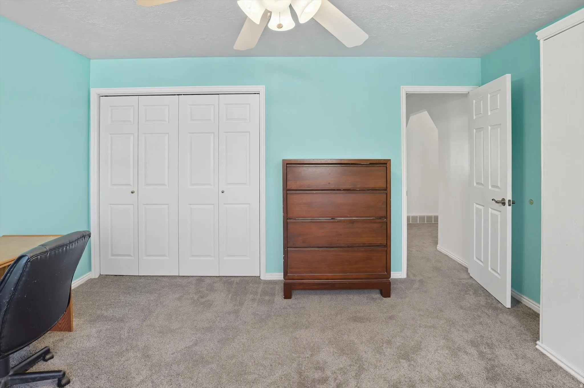 Carpeted home office with a textured ceiling and ceiling fan