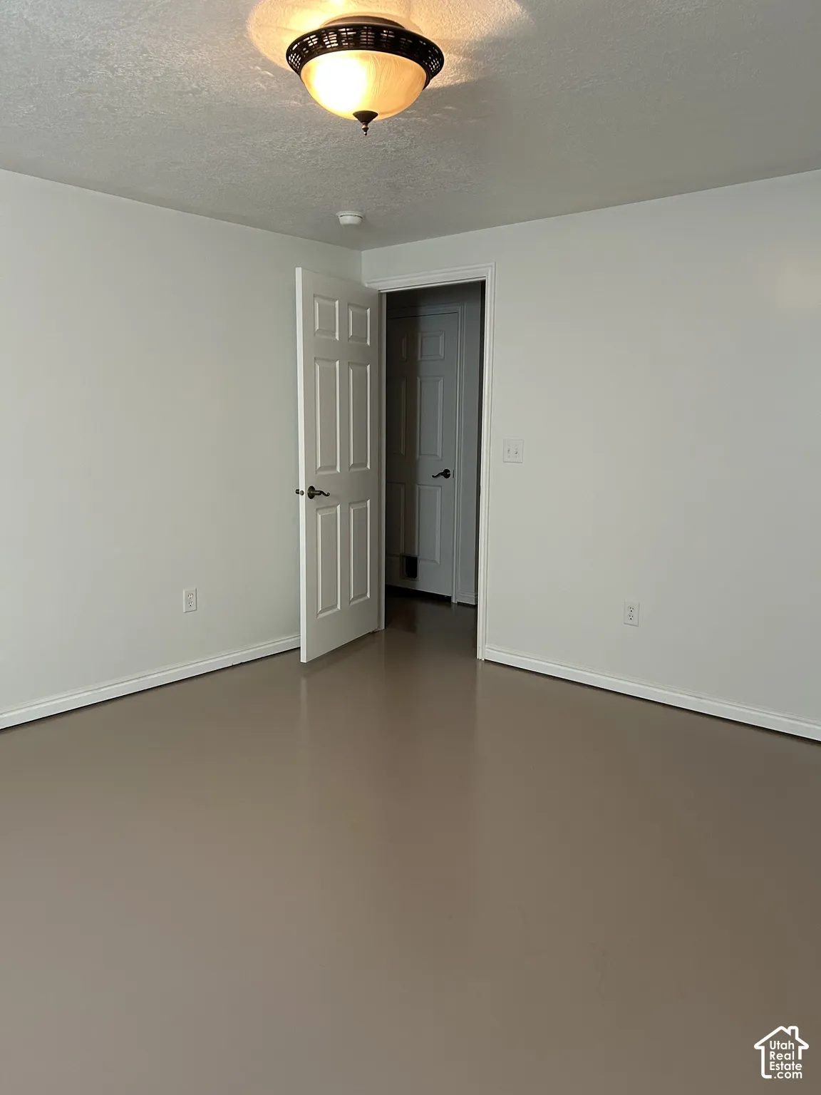 Room featuring neutral wall paint, smooth-finish flooring, a six-panel interior door, and a flush-mount dome light fixture