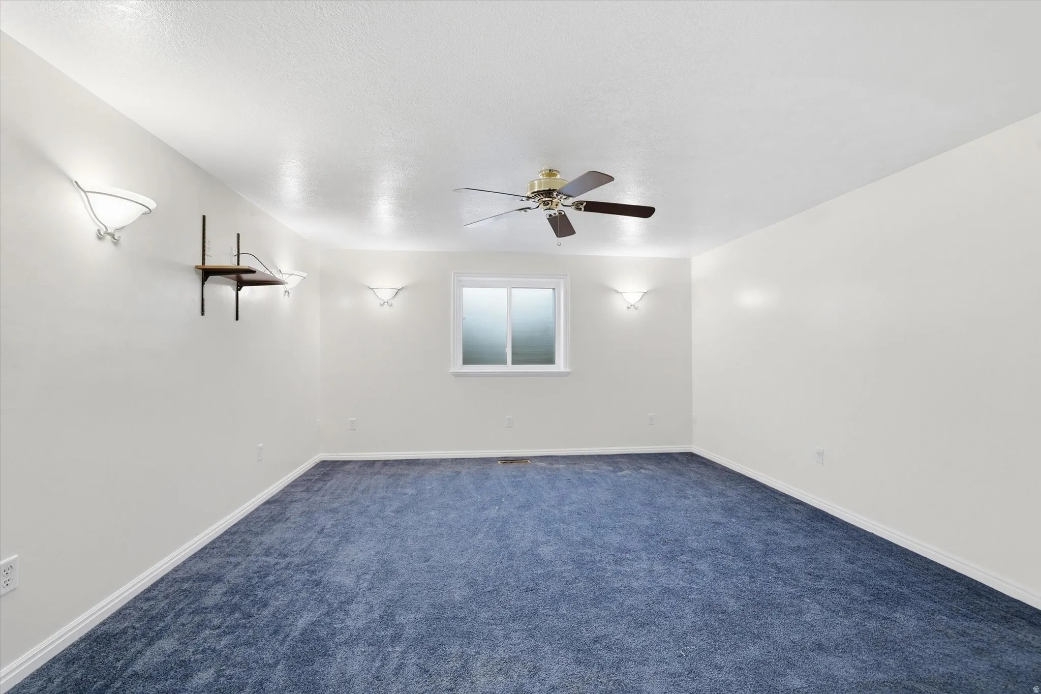 Empty room with dark carpet and ceiling fan