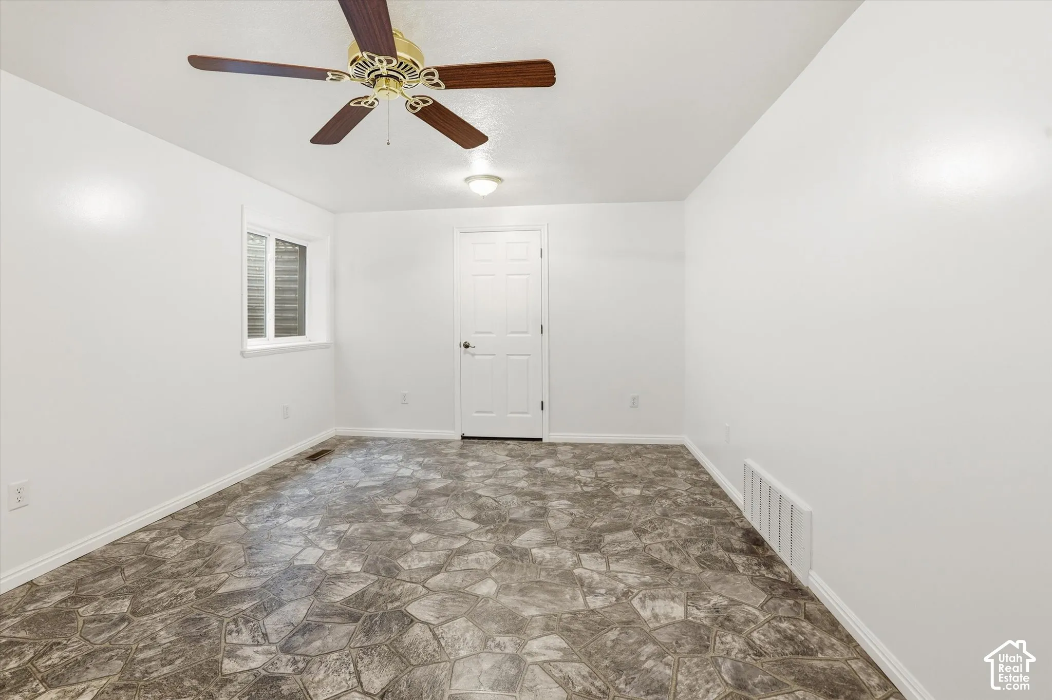 Spare room featuring stone floors and ceiling fan