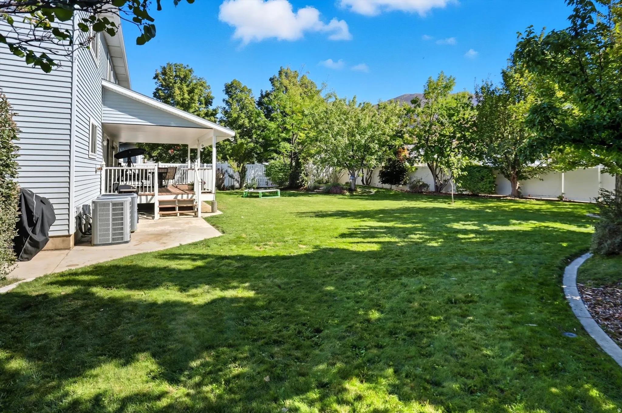 Fenced backyard with a trampoline and a wooden deck